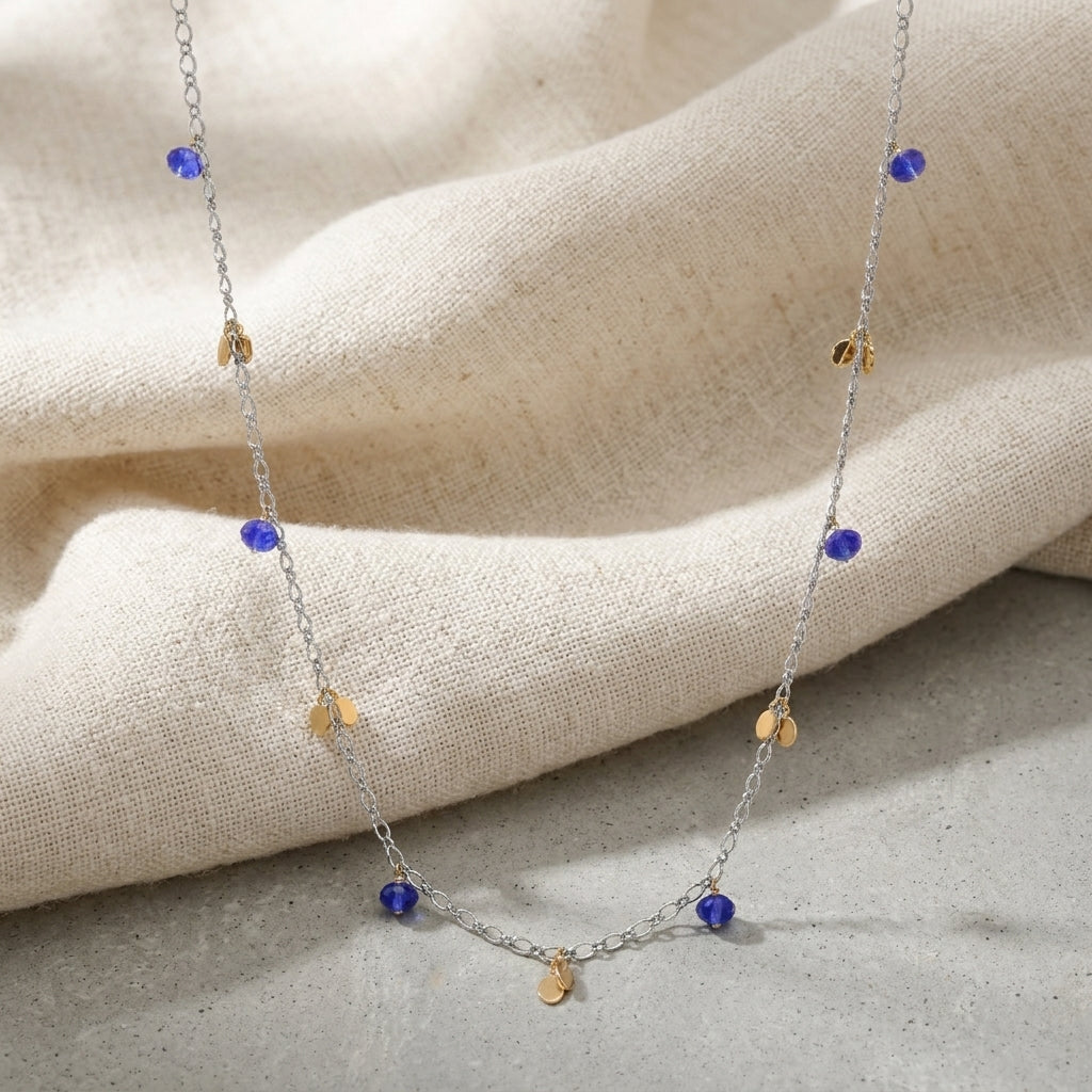 Faceted Blue Bead & Gold Charms Link Necklace on a beige fabric background
