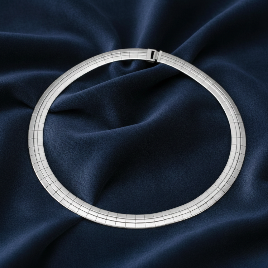 Silver necklace on a dark blue fabric background.