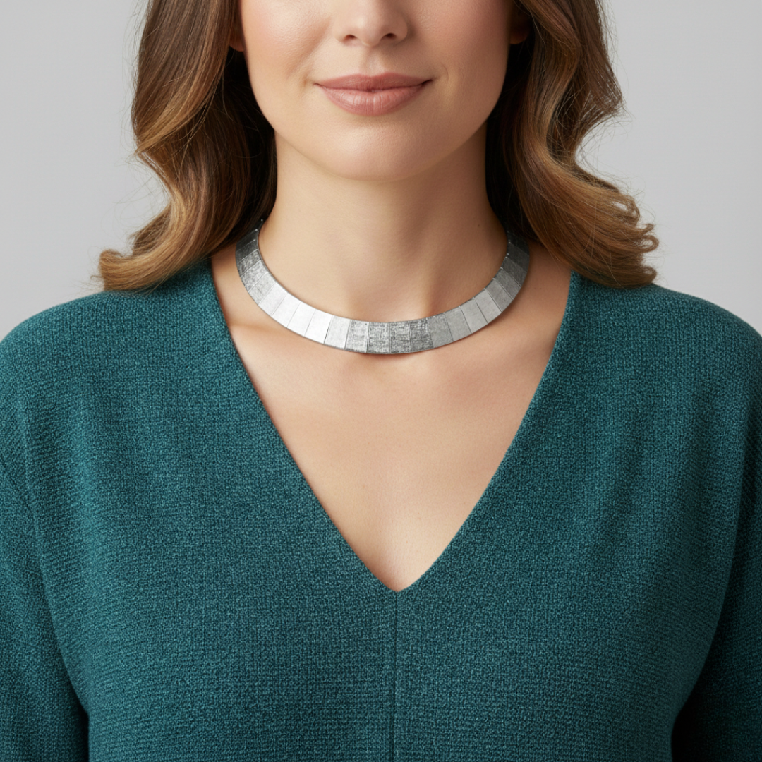 Woman wearing a silver necklace with a plain background