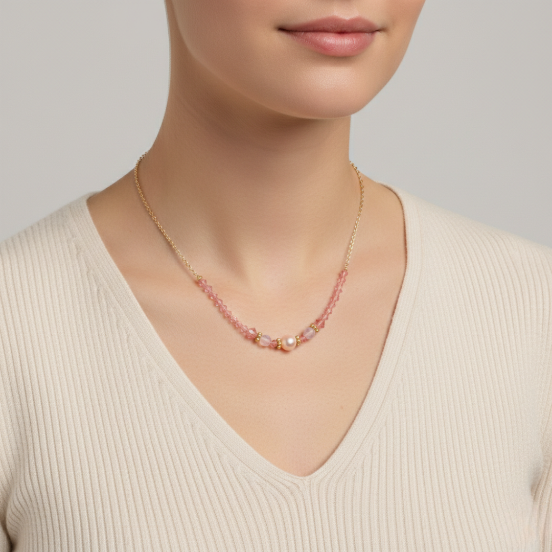 Necklace with pink beads worn by a person in a beige sweater on a neutral background
