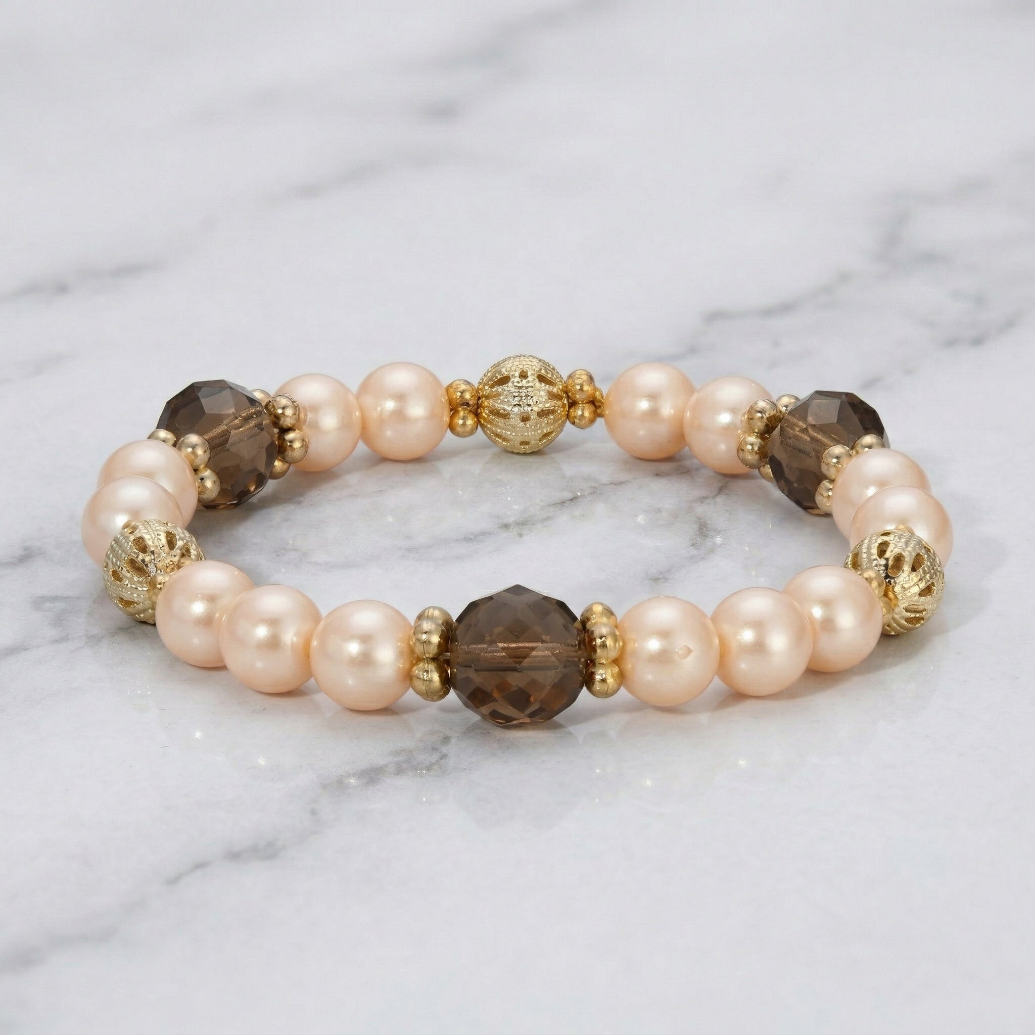 Beaded bracelet with pink, brown, and gold beads on a marble background