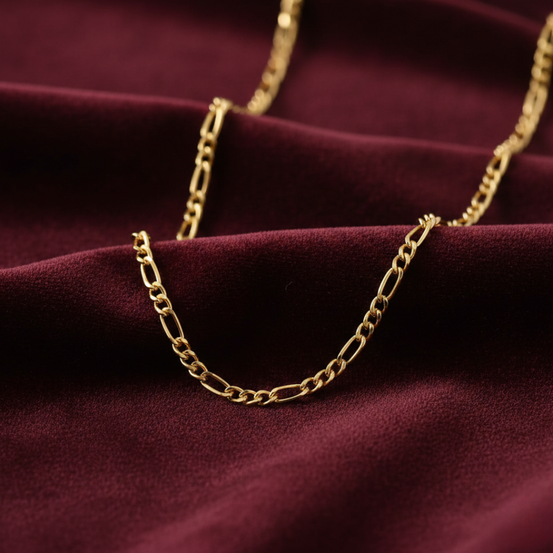 Gold chain necklace on a burgundy fabric background