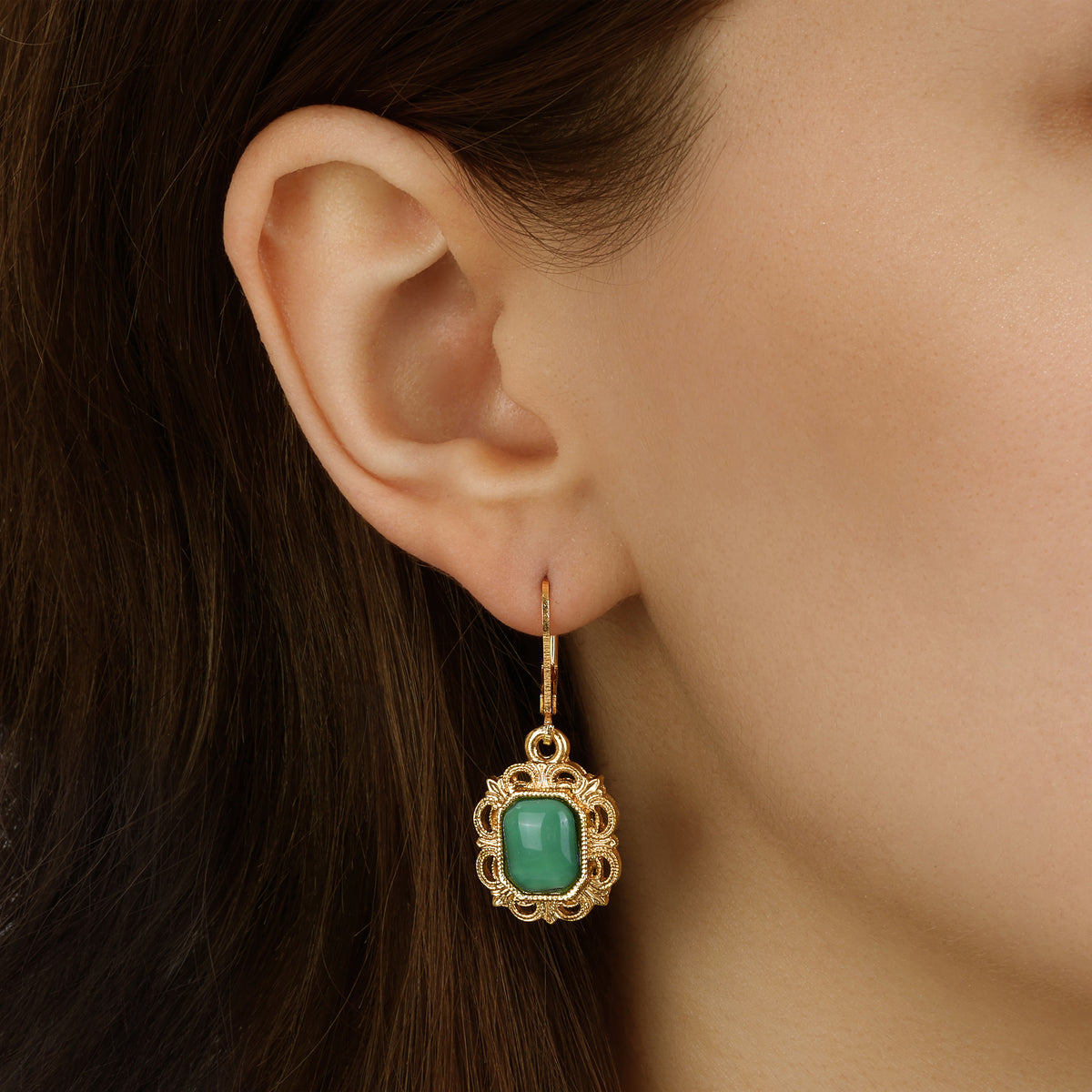 A close-up of a model's ear wearing a Green Octagon Moonstone & Gold Filigree Drop Earrings