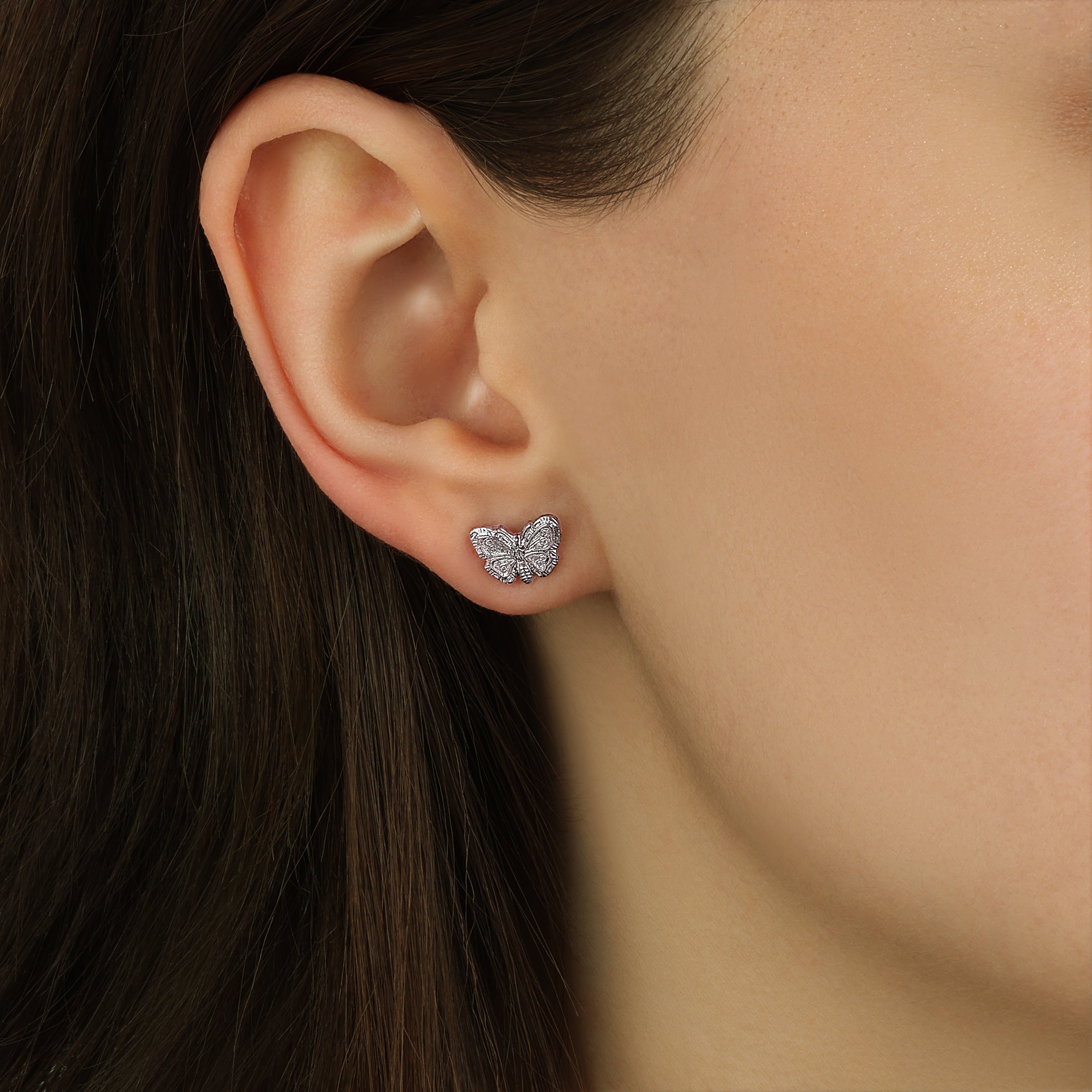 Close up of a woman wearing Petite Monarch Butterfly Silver Tone Stud Earrings