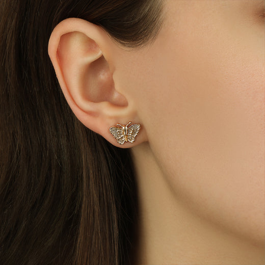 Close up of a woman wearing Dainty Gold Tone Butterfly Stud Earrings