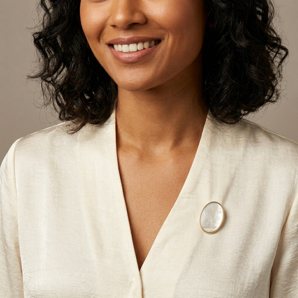 Woman wearing a beige blazer with a brooch on a neutral background