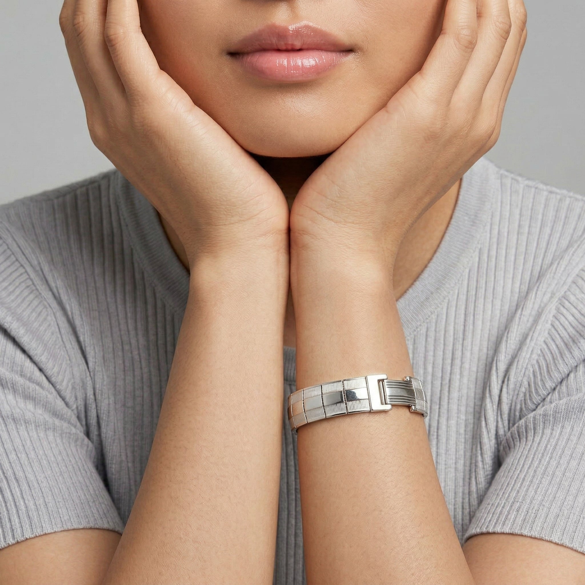 Person wearing a silver bracelet with a neutral background
