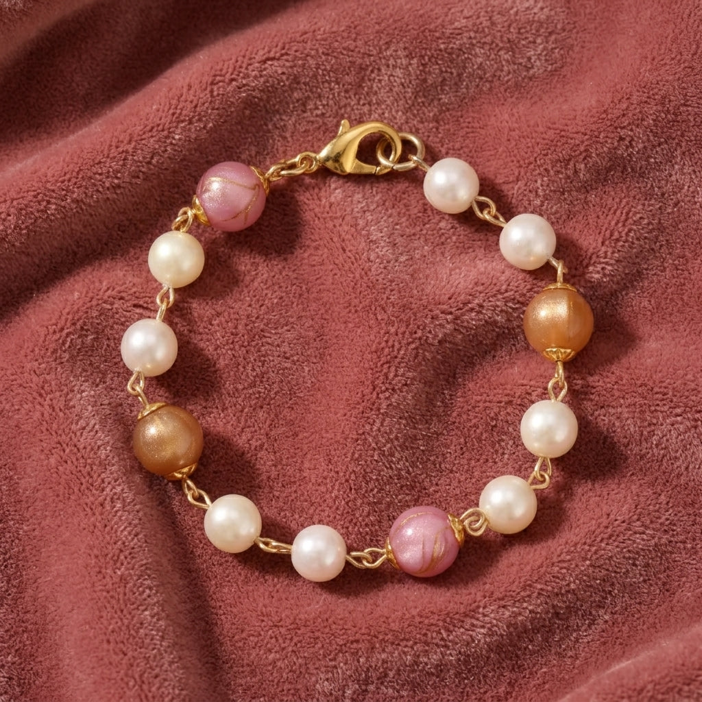 Gold tone pink peppermint and peach with white faux pearl beaded bracelet resting on dark pink fabric