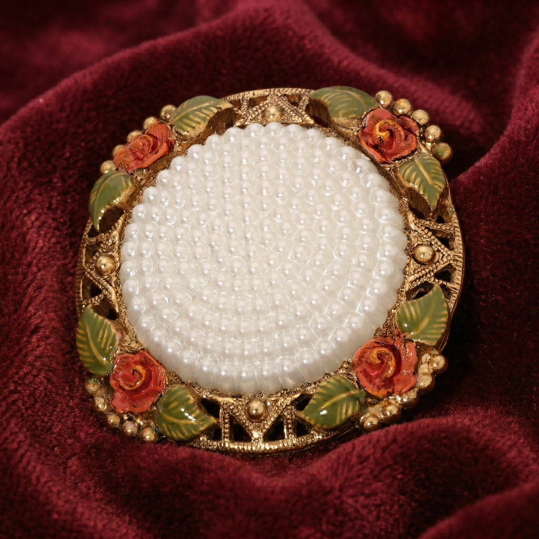 Decorative brooch with pearl center and floral design on a red fabric background