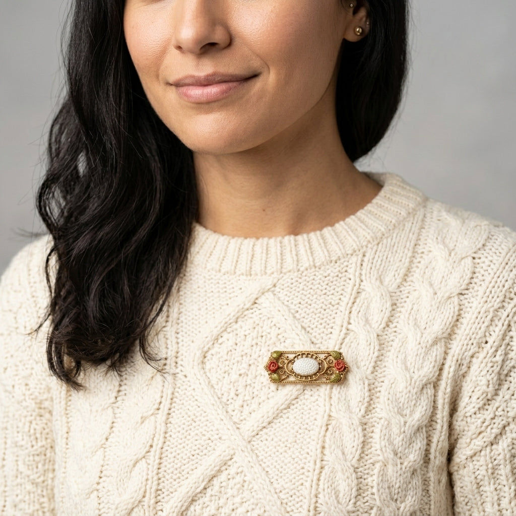 Woman wearing a cream sweater with a decorative floral brooch on a gray background