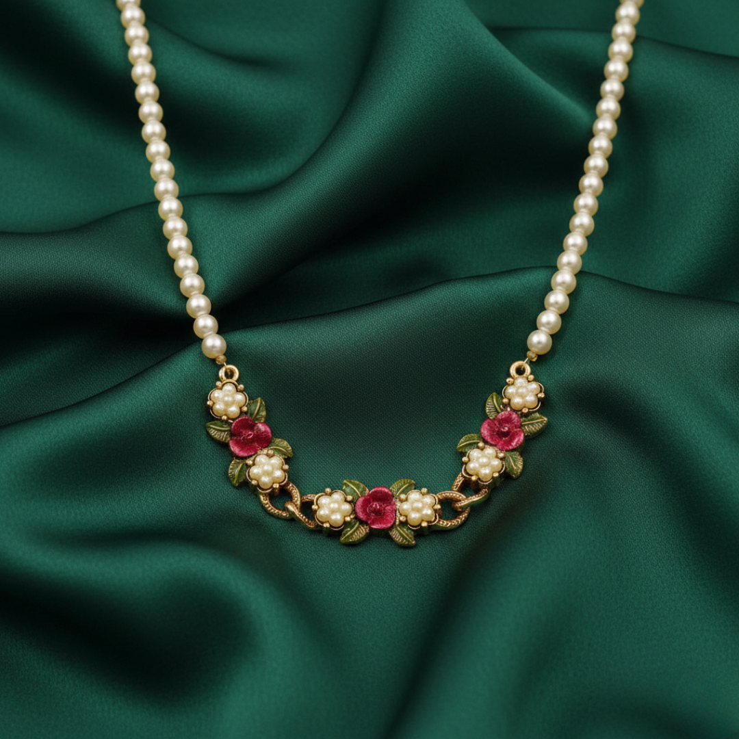 Faux pearl necklace with floral embellishments on a green fabric background