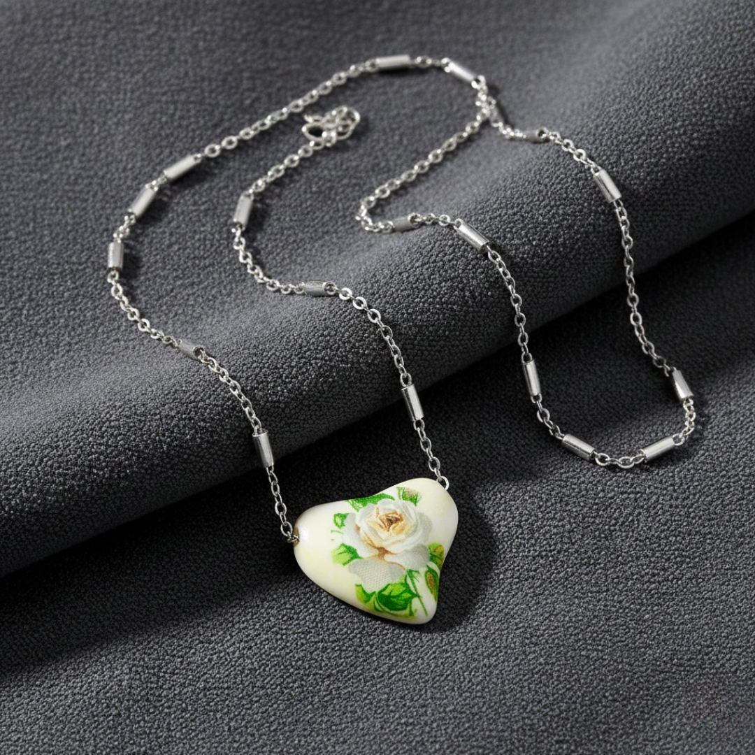 Necklace with a heart-shaped pendant featuring a white rose design on a dark surface