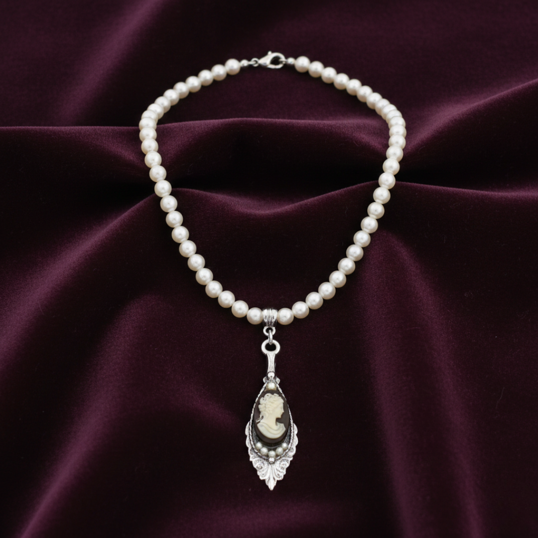 Pearl necklace with a cameo pendant on a purple fabric background.