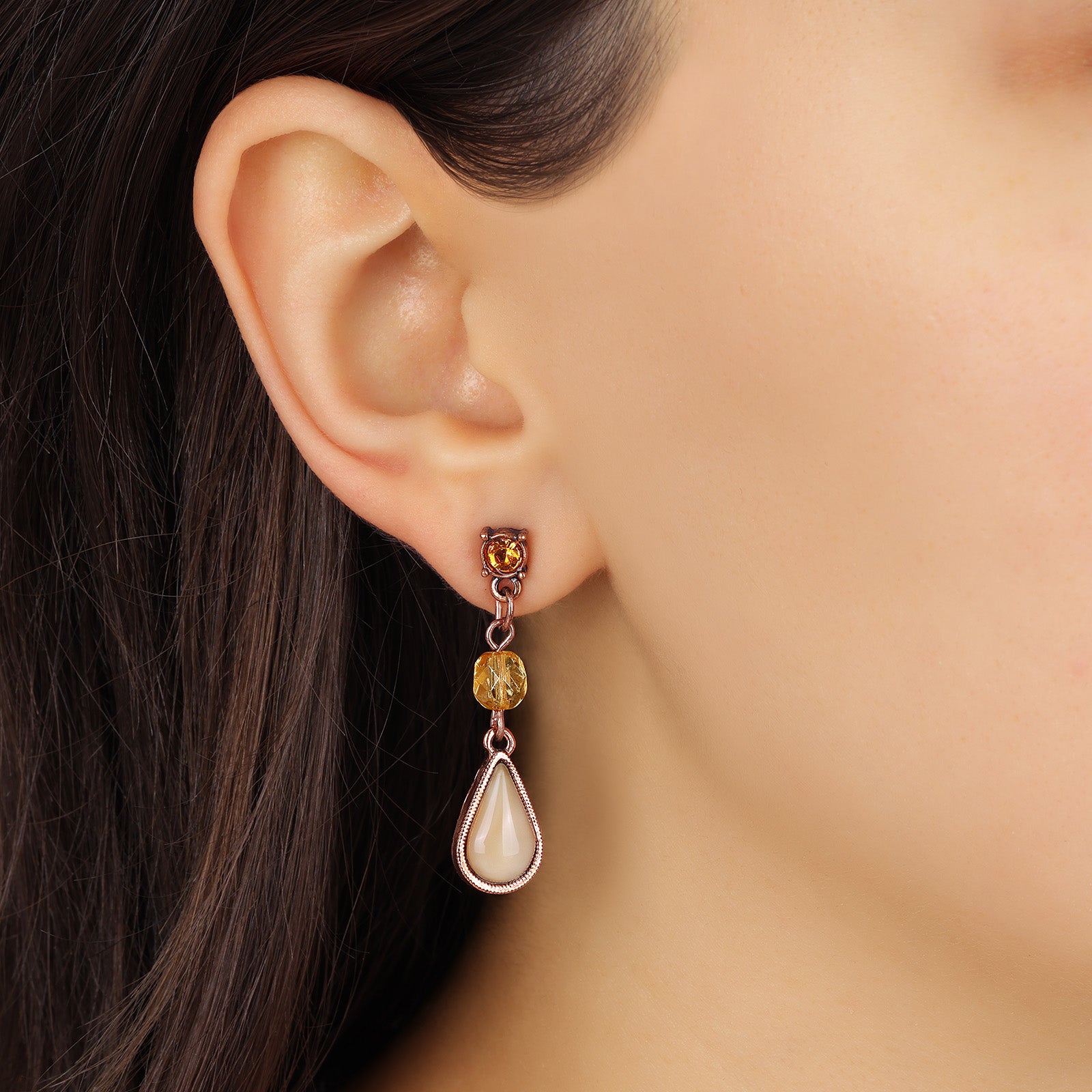 A close-up of a model's ear wearing a Rose Gold Topaz Crystal & Beige Moonstone Teardrop Dangle Stud Earrings