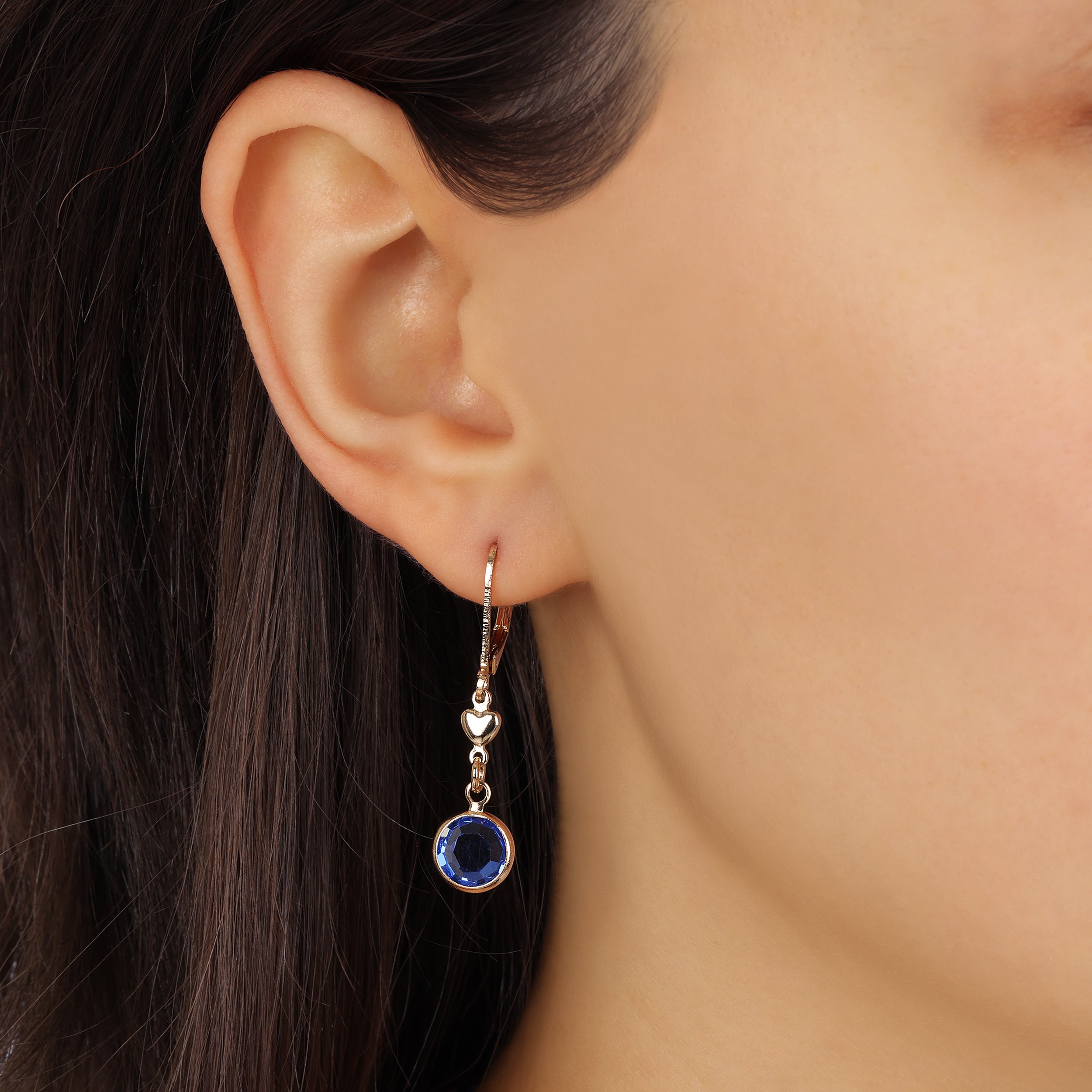 Close up of a woman wearing Golden Heart Channel Sapphire Blue Crystal Drop Earrings