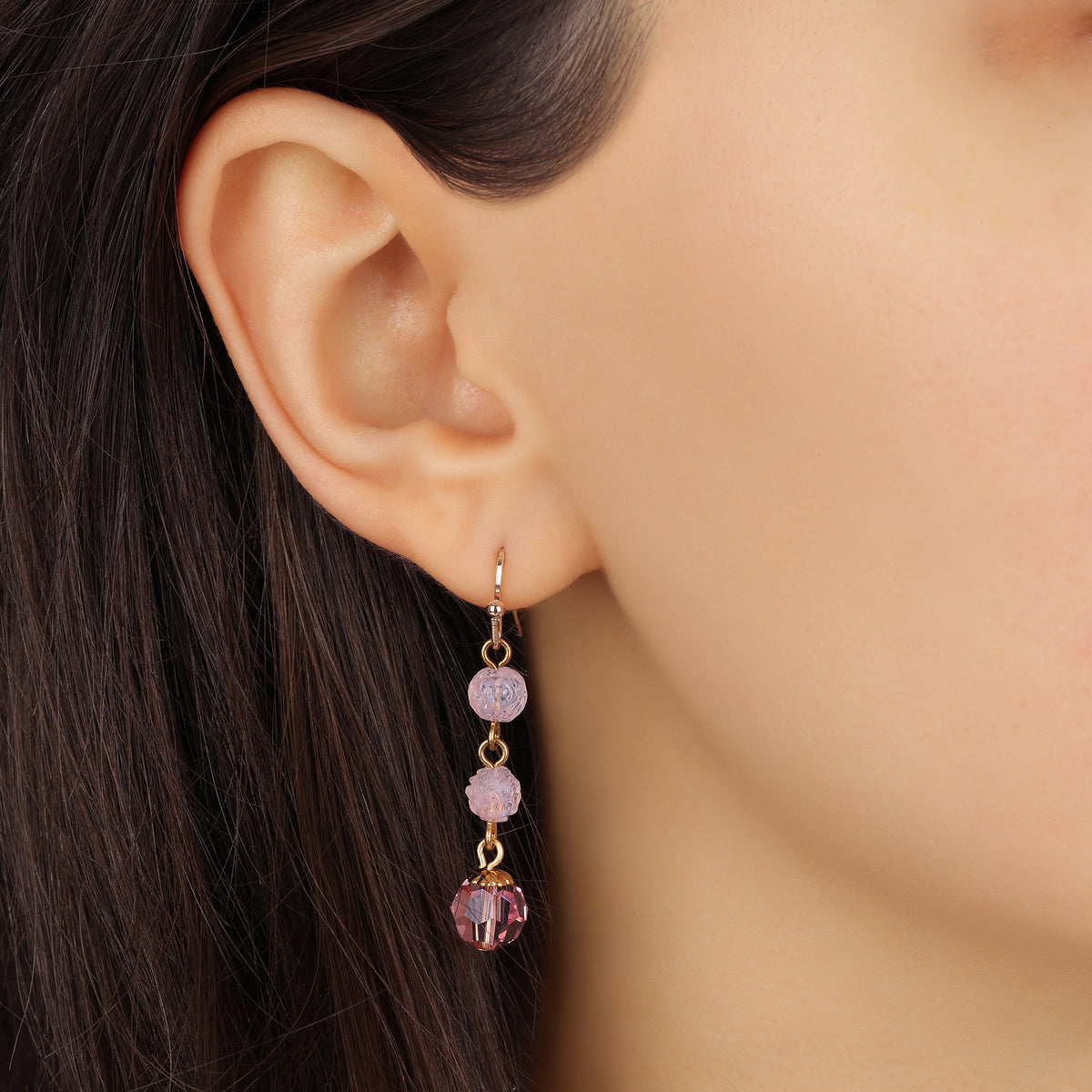 A close-up of a model's ear wearing a Golden Rose Pink Bead Drop & Dangle Earring