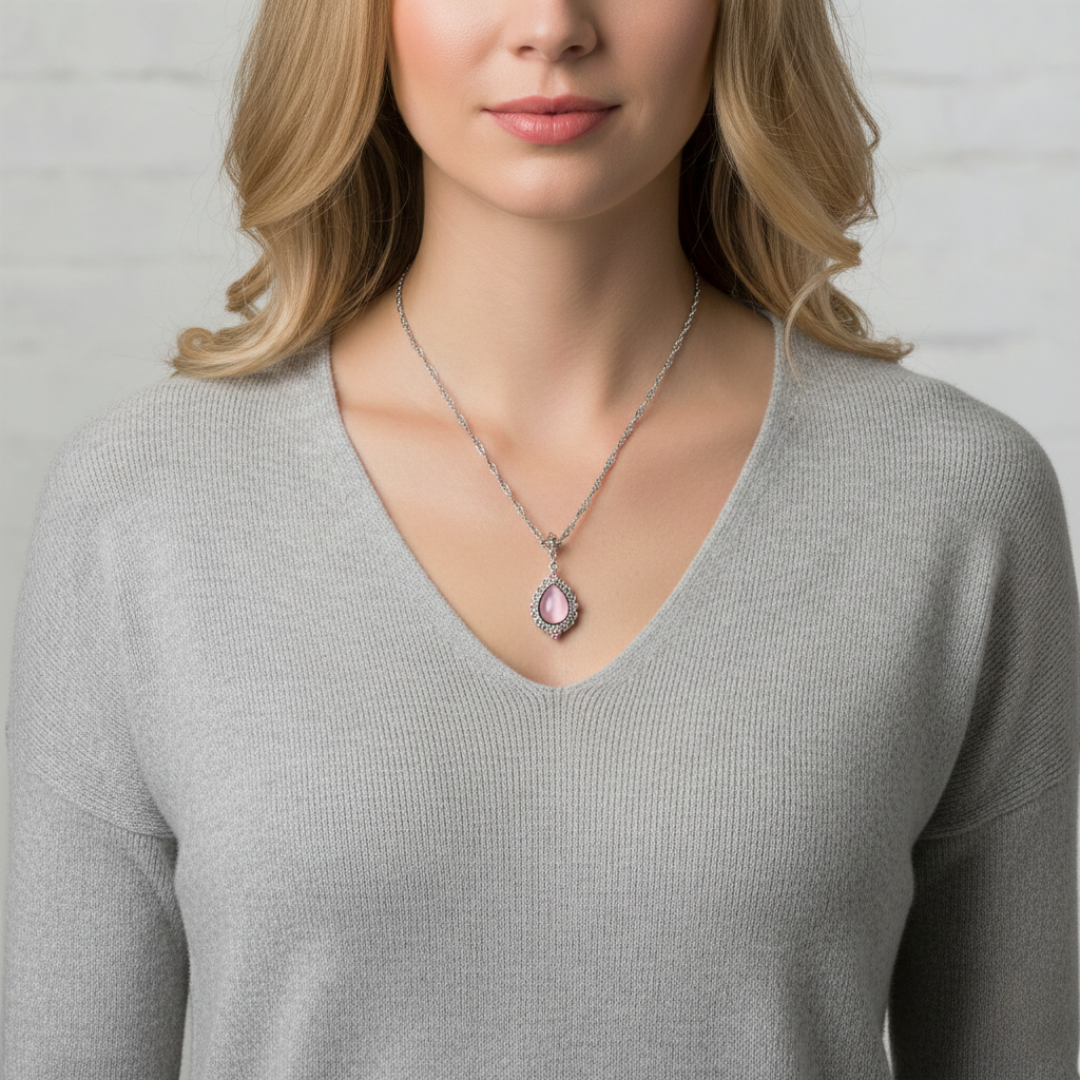 Woman wearing a necklace with a pink pendant against a neutral background