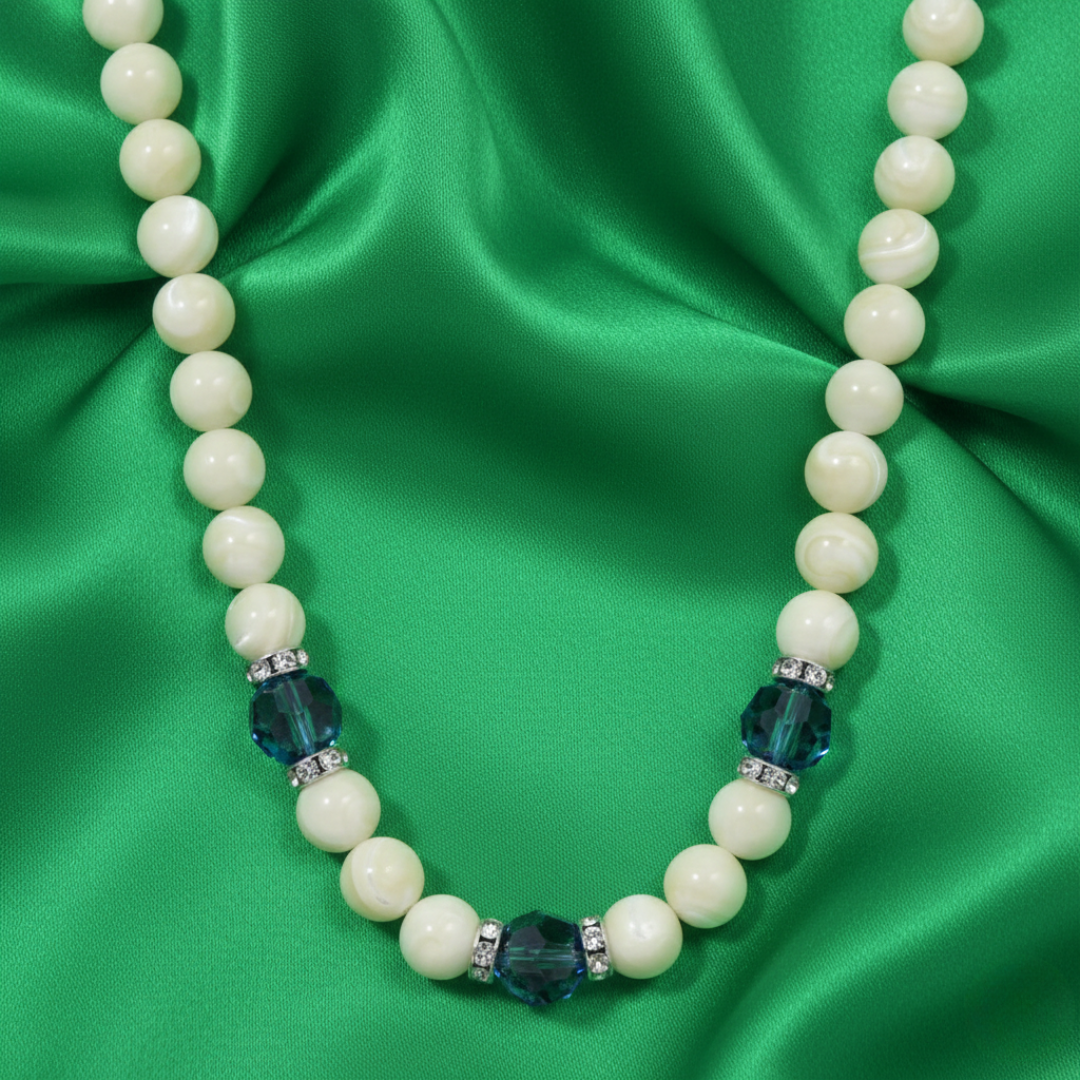 Necklace with white beads and blue accents on a green satin background
