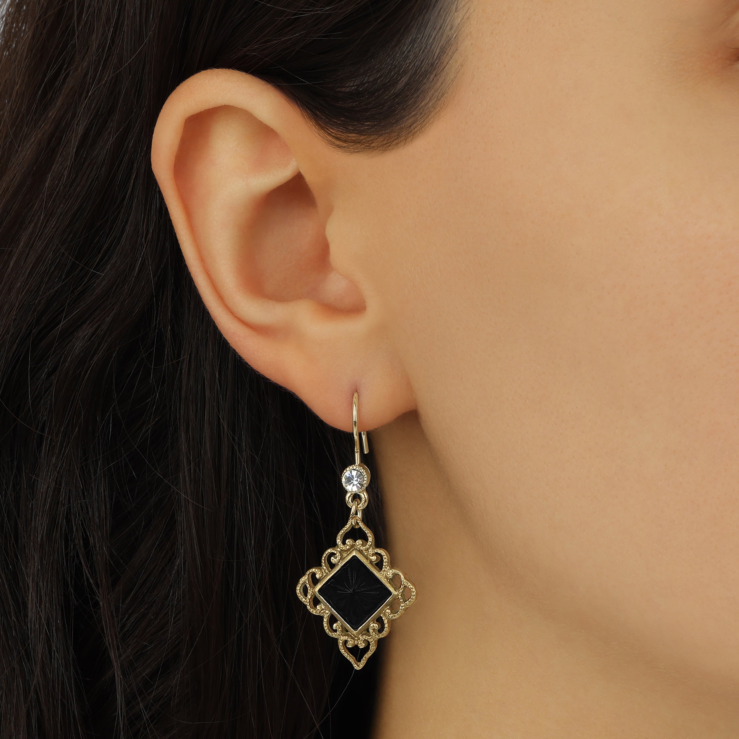 A close-up of a model's ear wearing Gold Filigree & Diamond Shaped Black Onyx Gemstone Drop Earrings