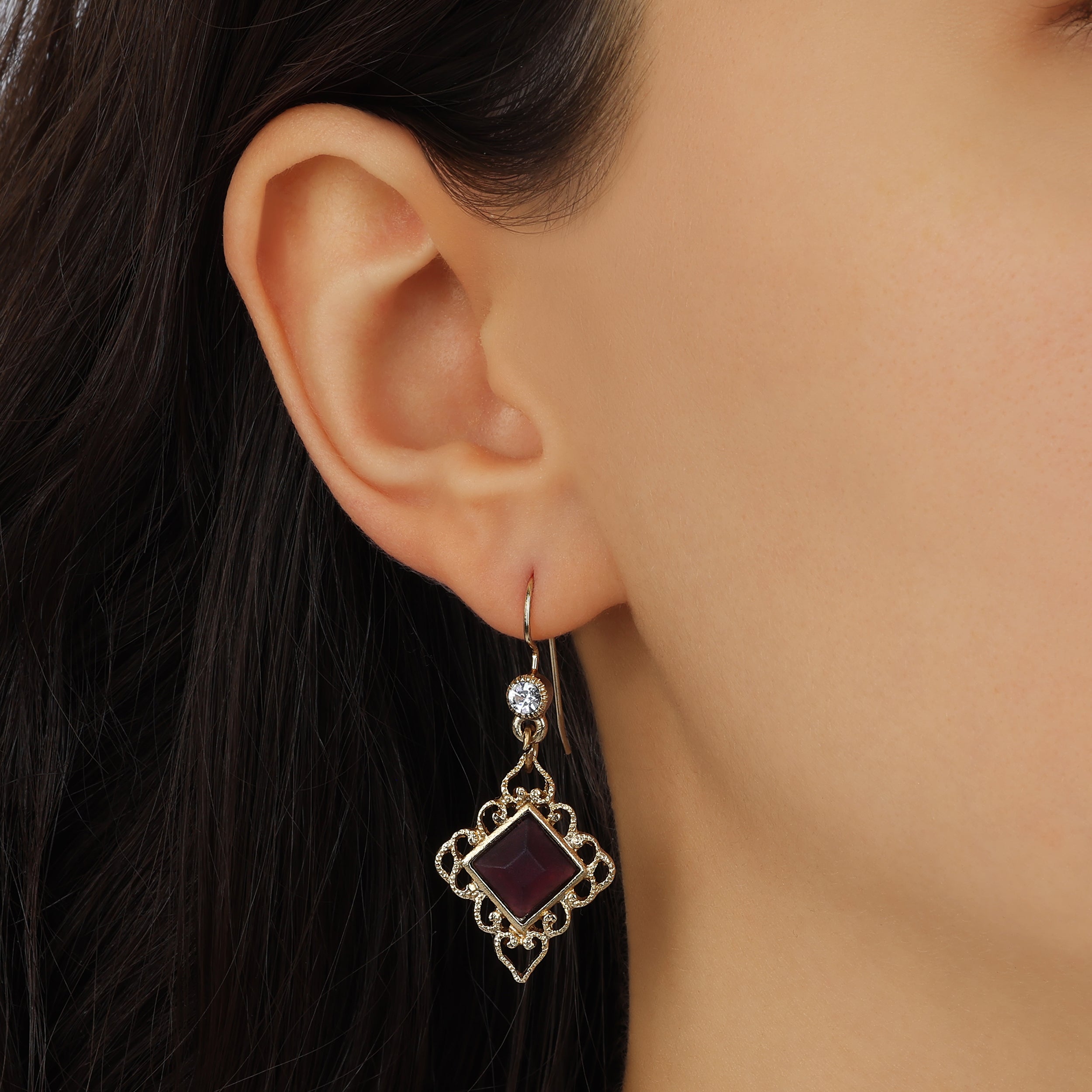 A close-up of a model's ear wearing Gold Filigree & Diamond Shaped Purple Amethyst Gemstone Drop Earrings