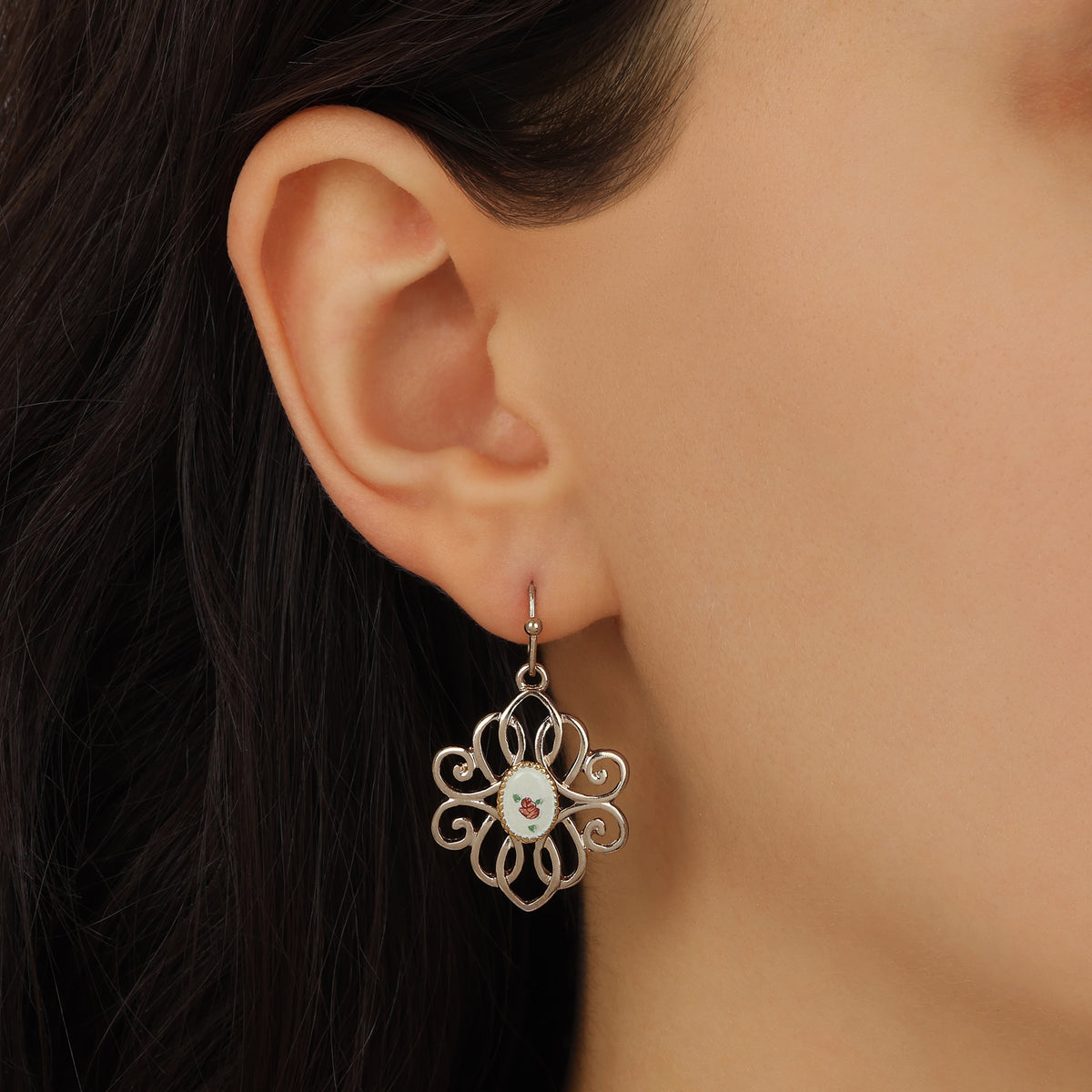 A close-up of a person's ear wearing a Golden Filigree & Oval Flower Decal Drop Earrings