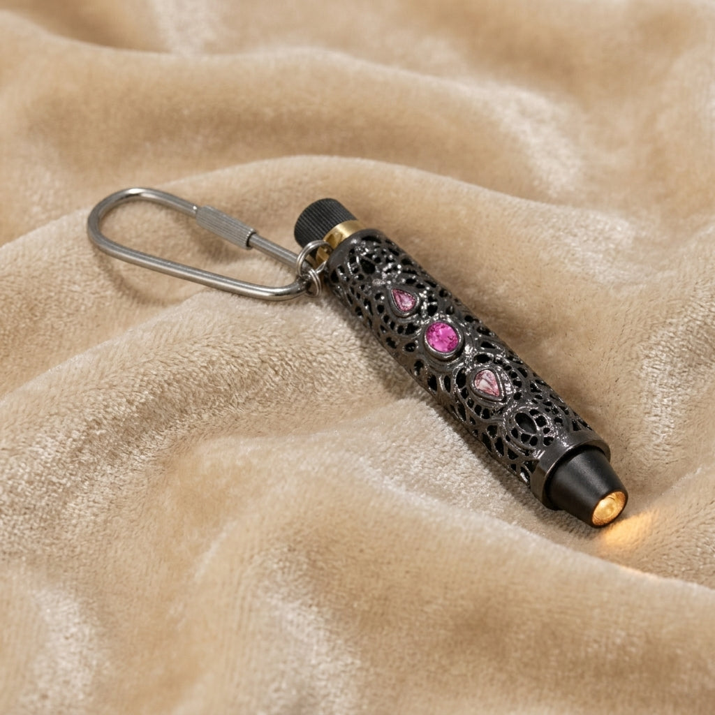 Pink crystal stone accented flashlight keychain resting on beige fabric