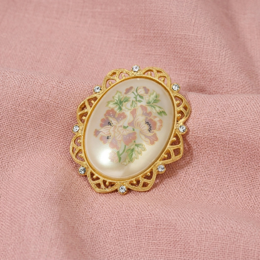 Golden Oval Faux Pearl Stone Floral Decal Pin resting on pink linen fabric