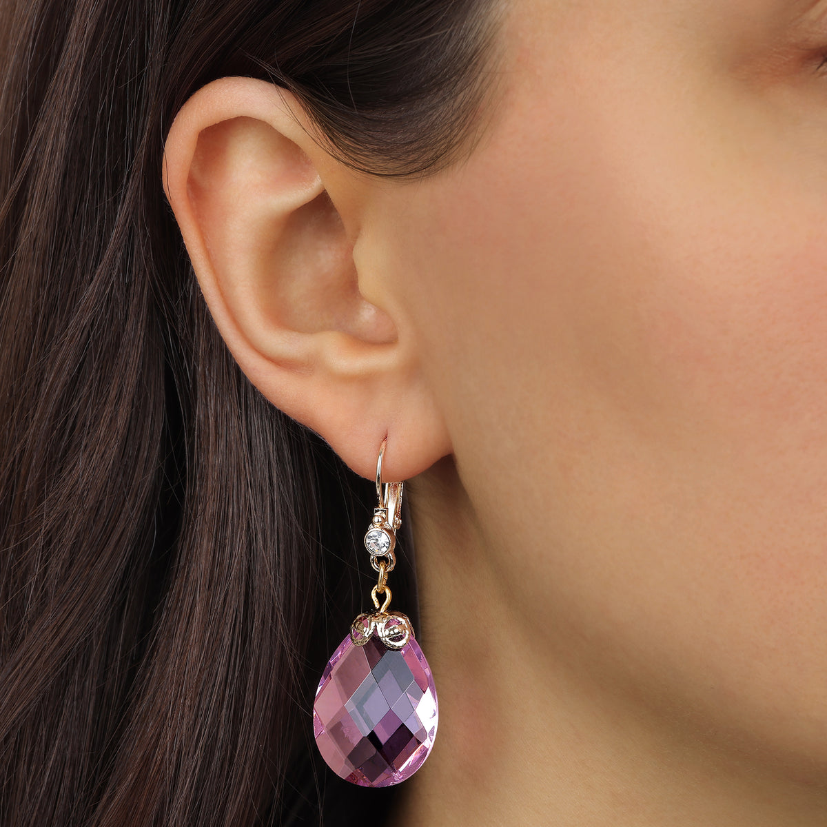 A close-up of a woman's ear wearing a Gold Tone Multi-Faceted Pink Briolette Crystal Stone Drop & Dangle Earrings