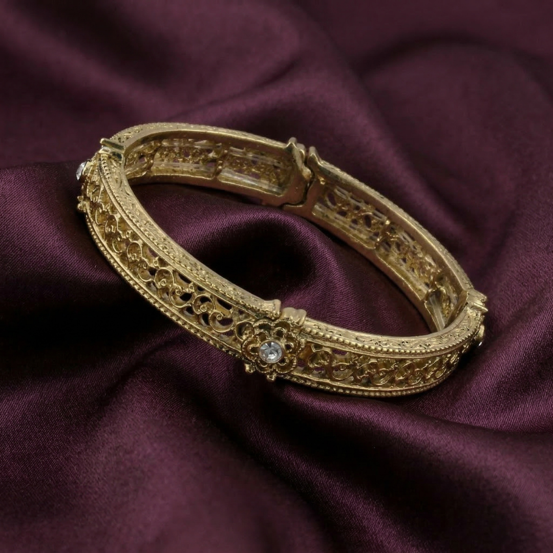 Gold bracelet with intricate design on a purple fabric background