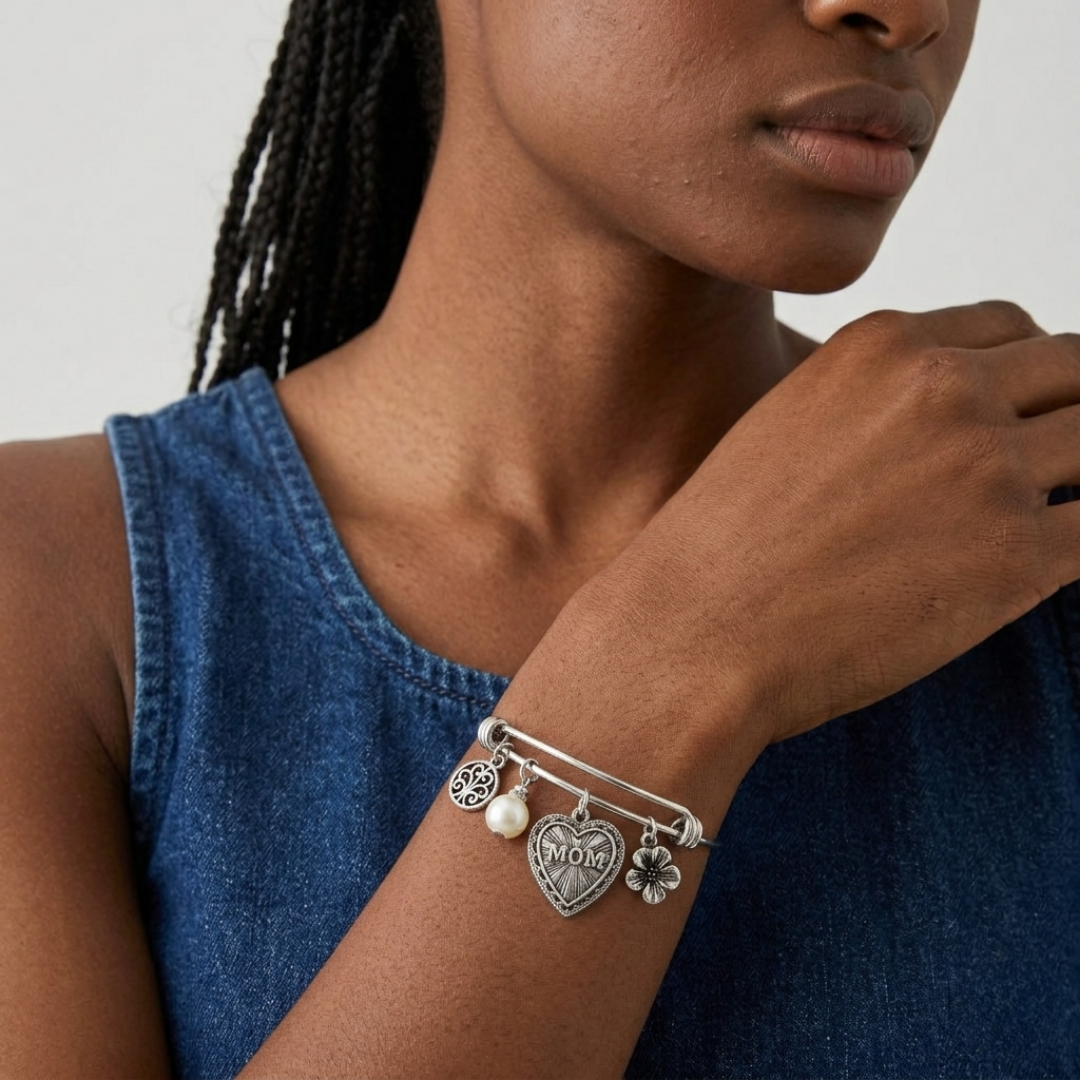 Woman wearing a silver bracelet with Mother's Day charms on a neutral background