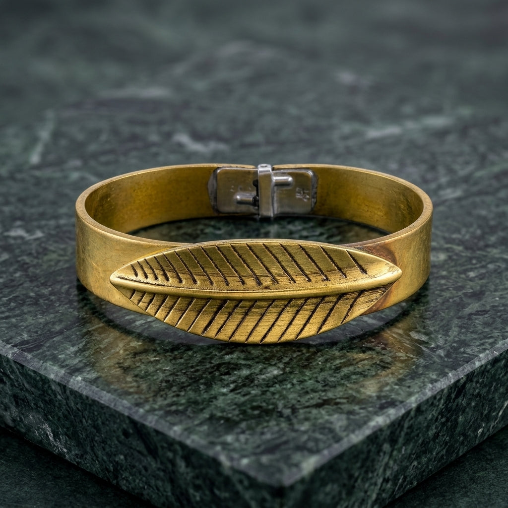 Gold tone BoHo style bracelet with feather design on a dark stone surface