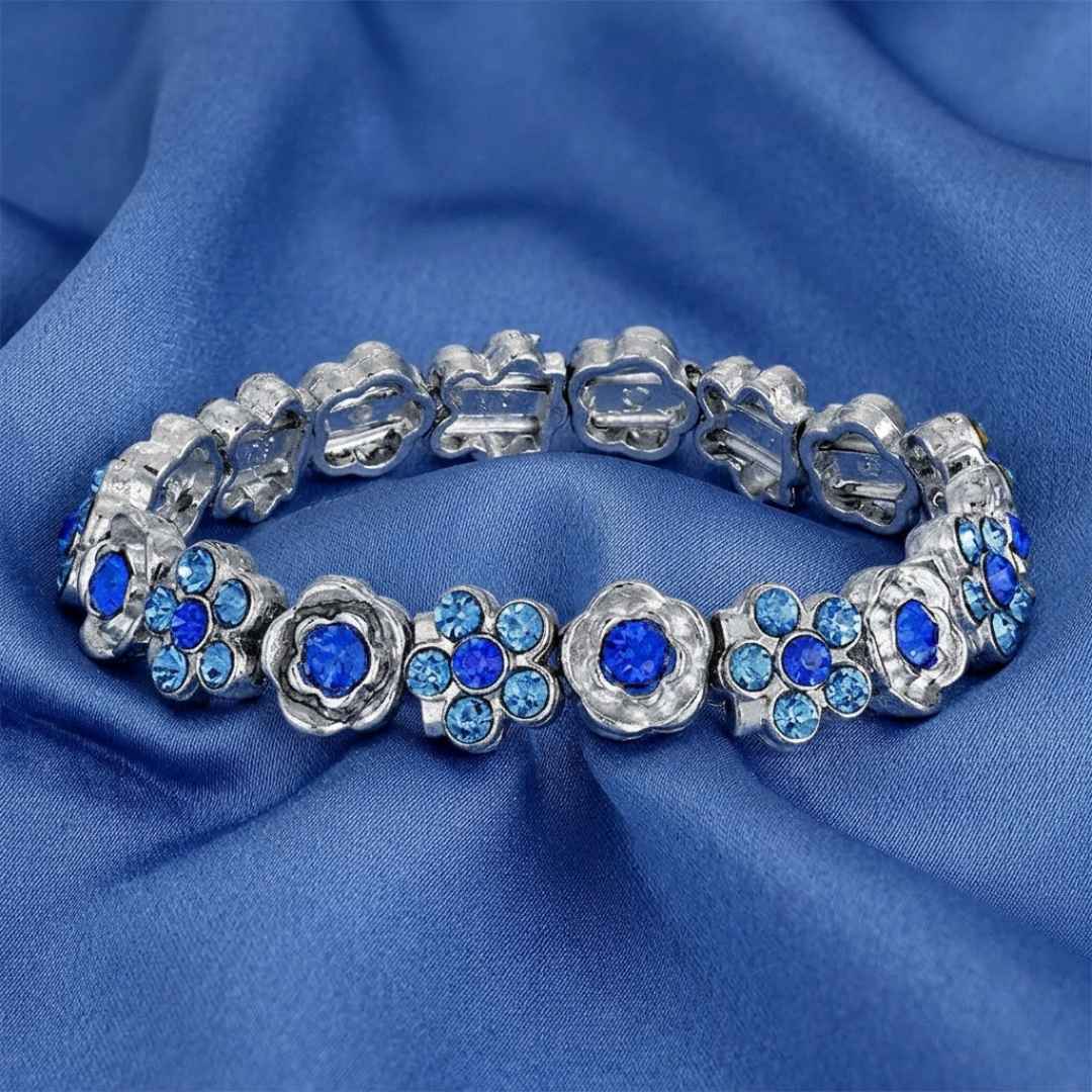 Silver floral bracelet with blue crystals on a blue fabric background