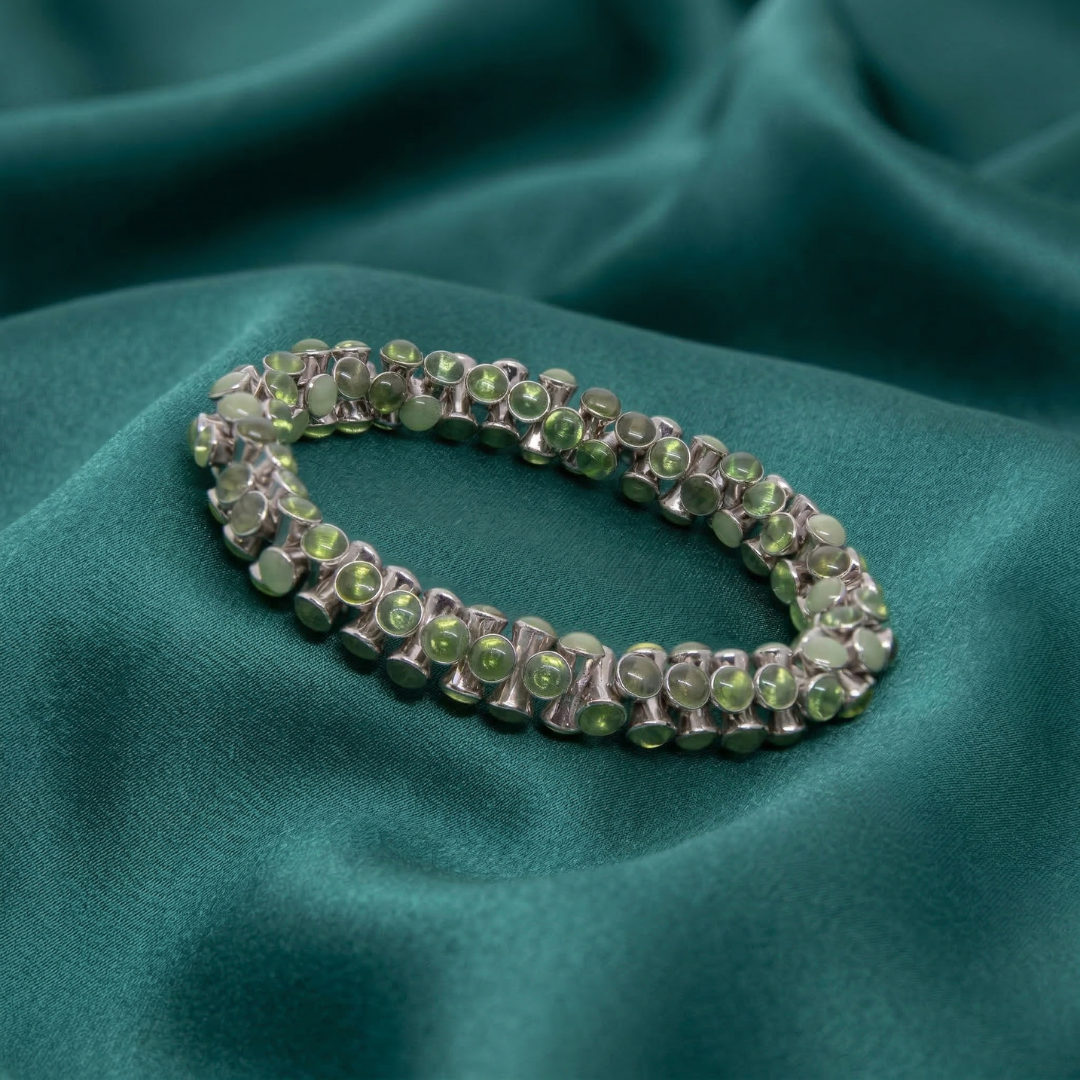 Bracelet with green crystals on a teal fabric background