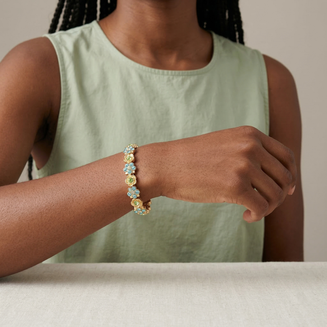 Person wearing a colorful bracelet with blue and green crystals on a neutral background