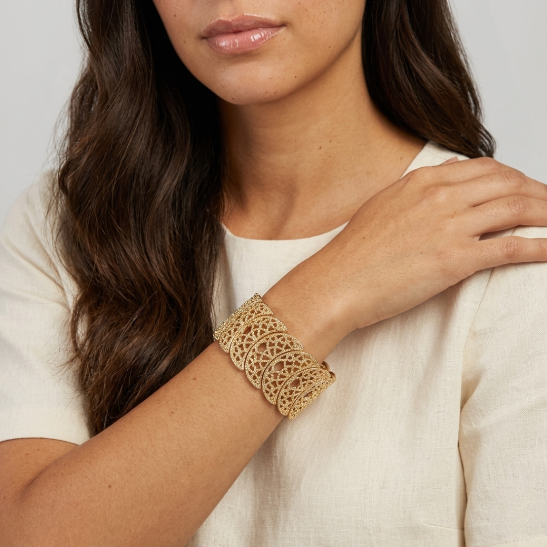 Woman wearing a gold filigree bracelet on a neutral background