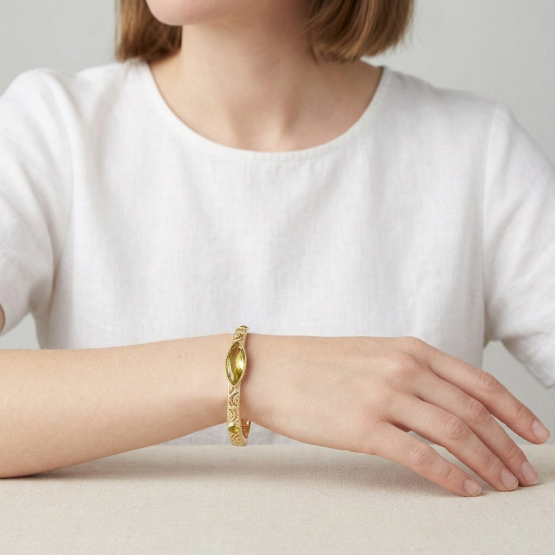 Person wearing a gold bracelet on a plain background