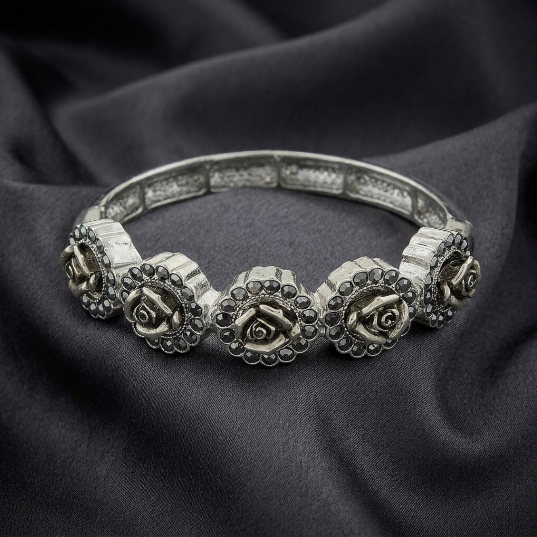 Silver bracelet with rose designs on a dark fabric background