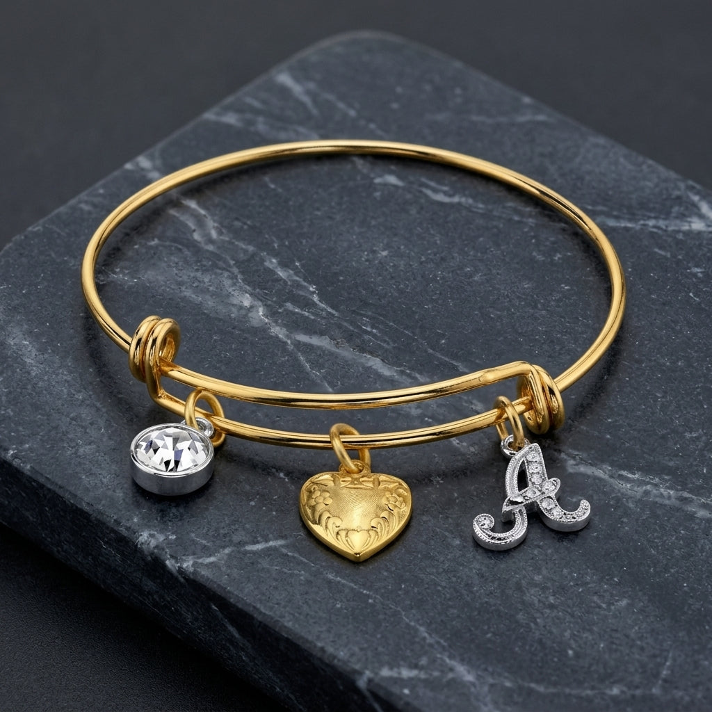 Gold Heart Initial Crystal Charm Bangle Bracelet resting on dark marble surface