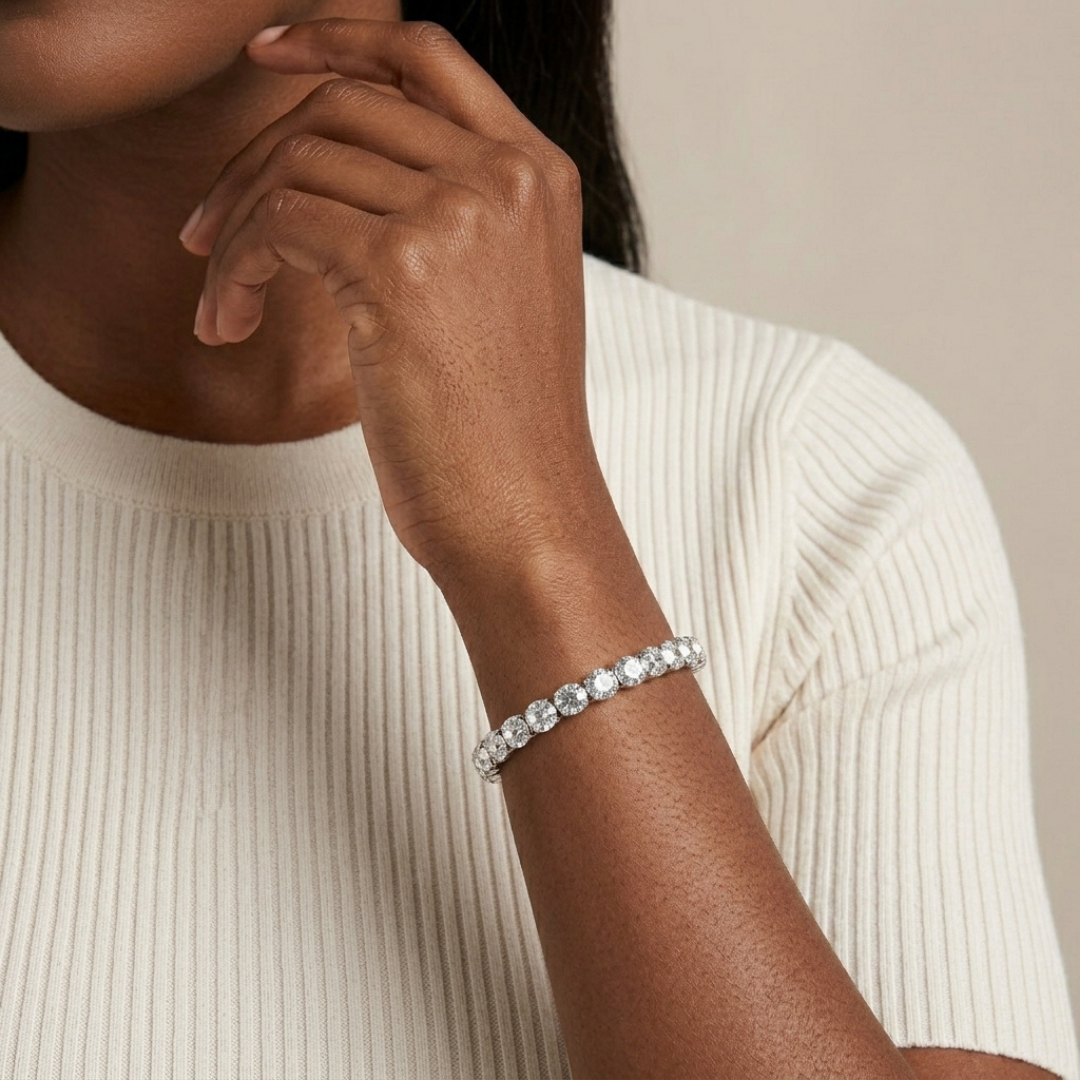 Close-up of a person wearing a clear crystal bracelet on a neutral background