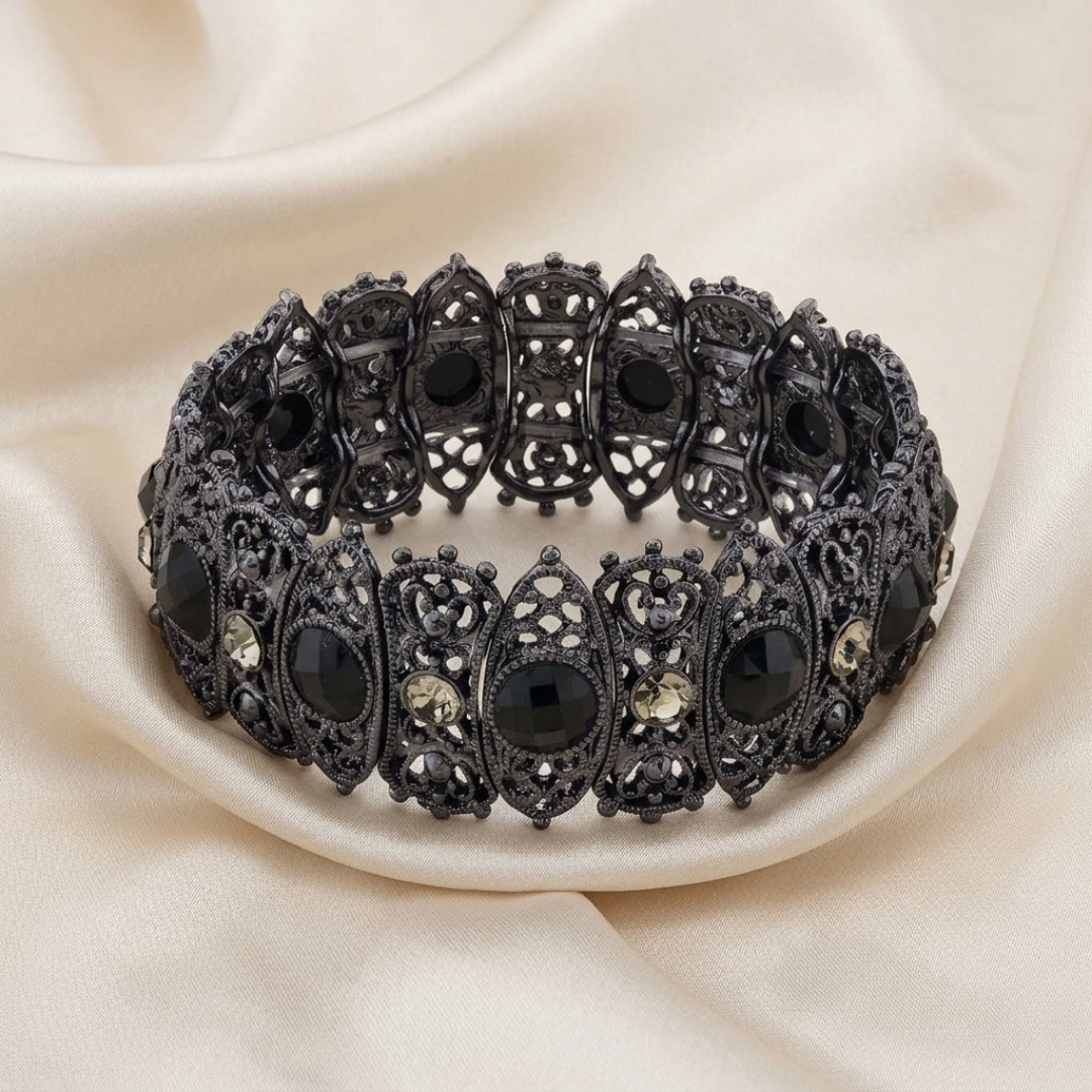 Decorative black bracelet with intricate designs on a beige fabric background
