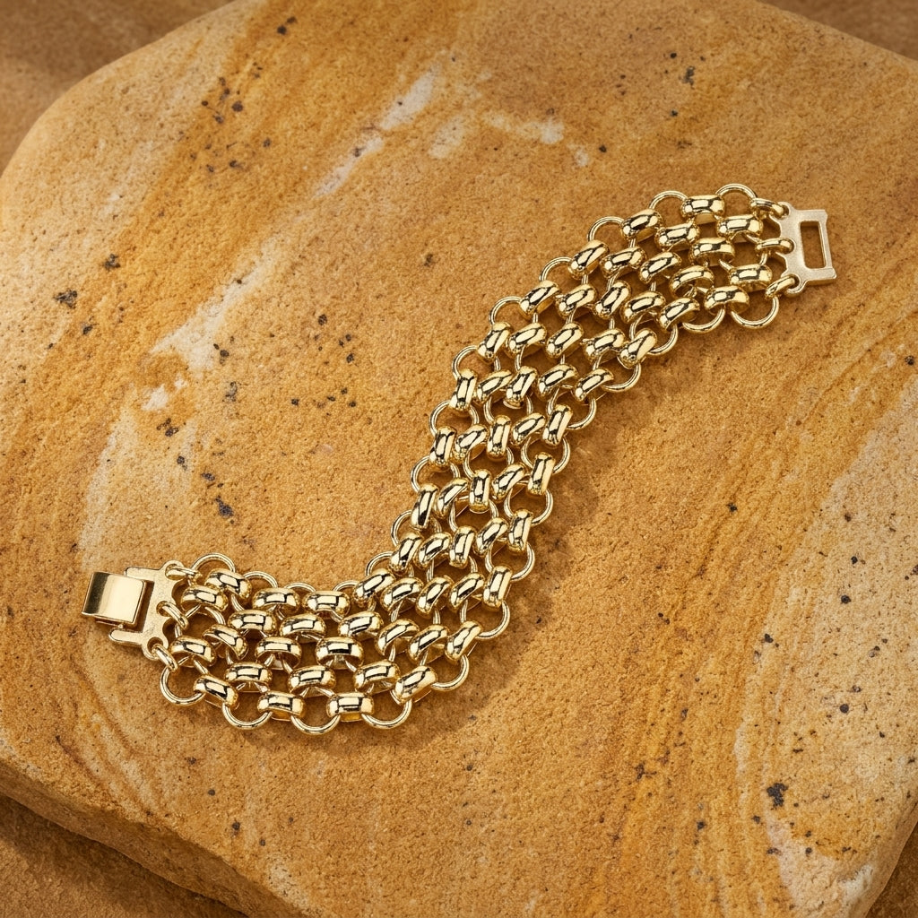 Polished Gold Mesh Chain Bracelet on a textured stone surface