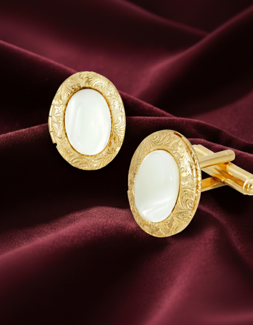 Gold cufflinks with white stones on a burgundy fabric background