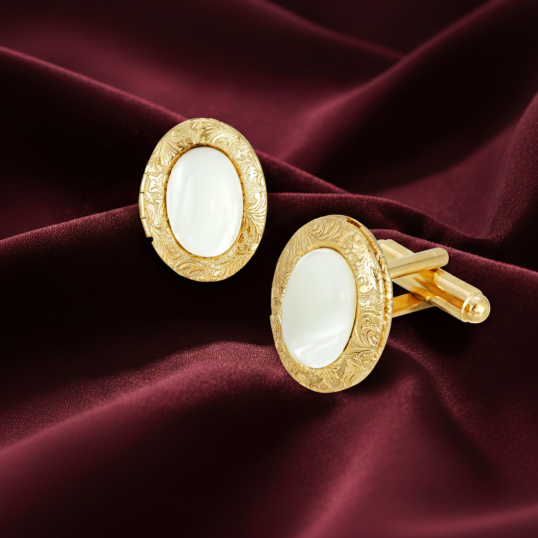 Gold cufflinks with white stones on a burgundy fabric background