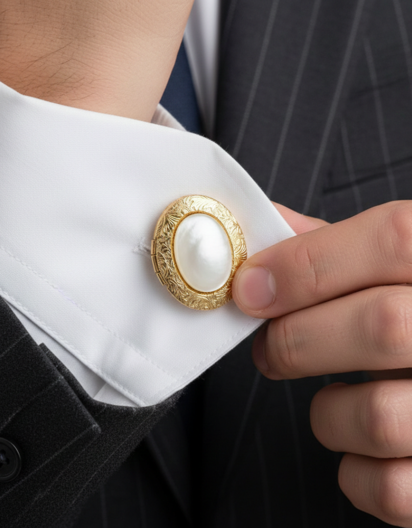 Gold cufflink with a white, semi-precious gemstone on a white shirt cuff.