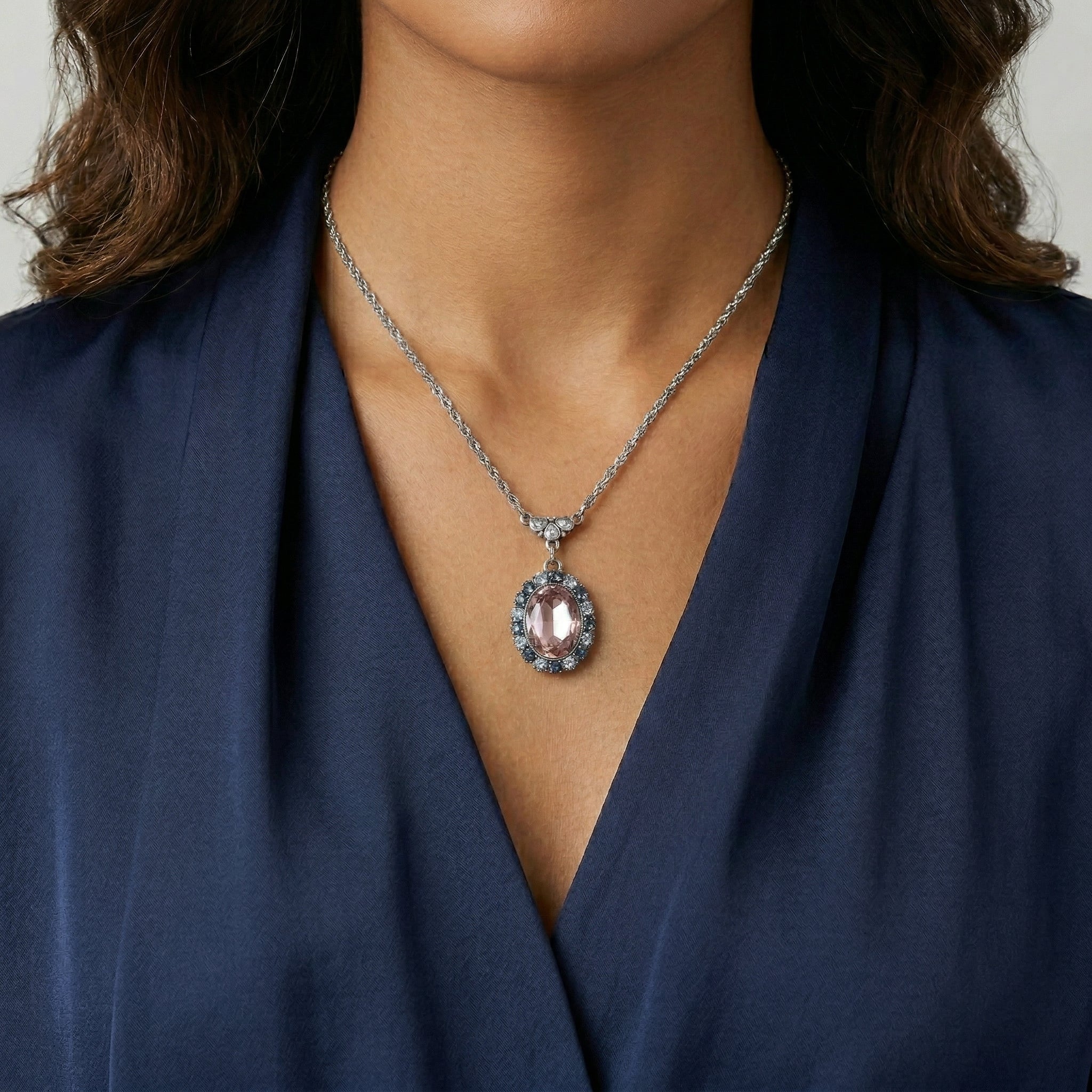 Woman in a navy blue top wearing a Anastasia Blue Rimmed Pink Oval Pendant Necklace