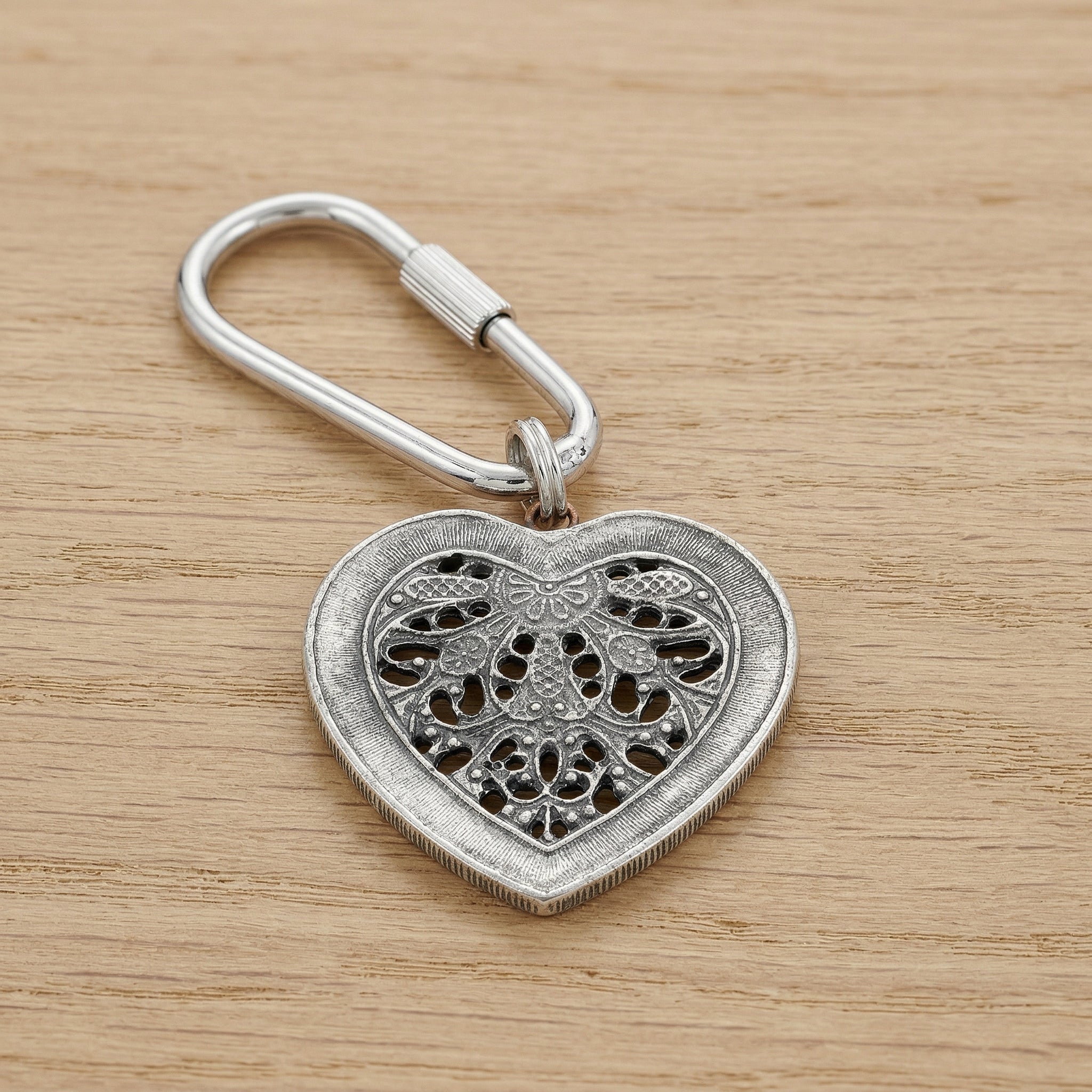 Silver tone Filigree Heart Carabiner Key Chain on a wooden surface