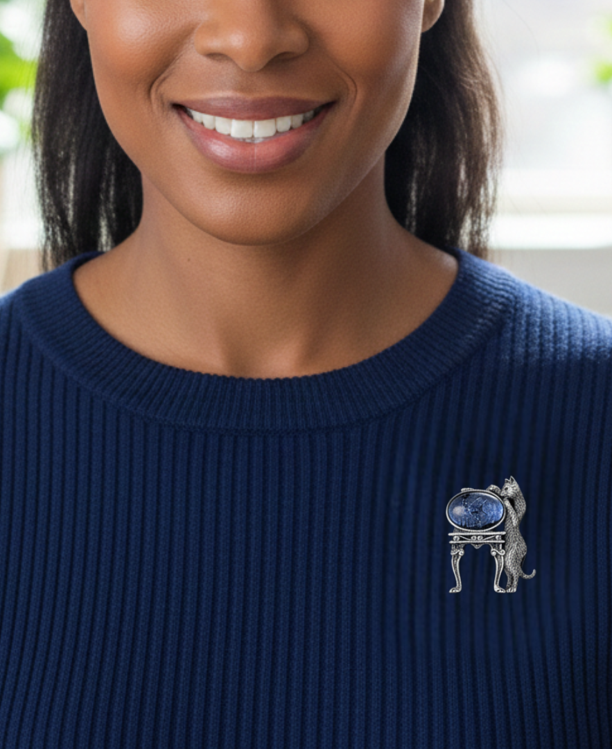 Woman wearing a blue sweater with a decorative brooch featuring a blue stone and silver metal.