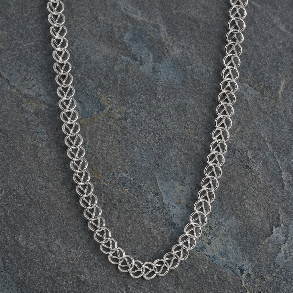Silver chain necklace on a textured gray stone background