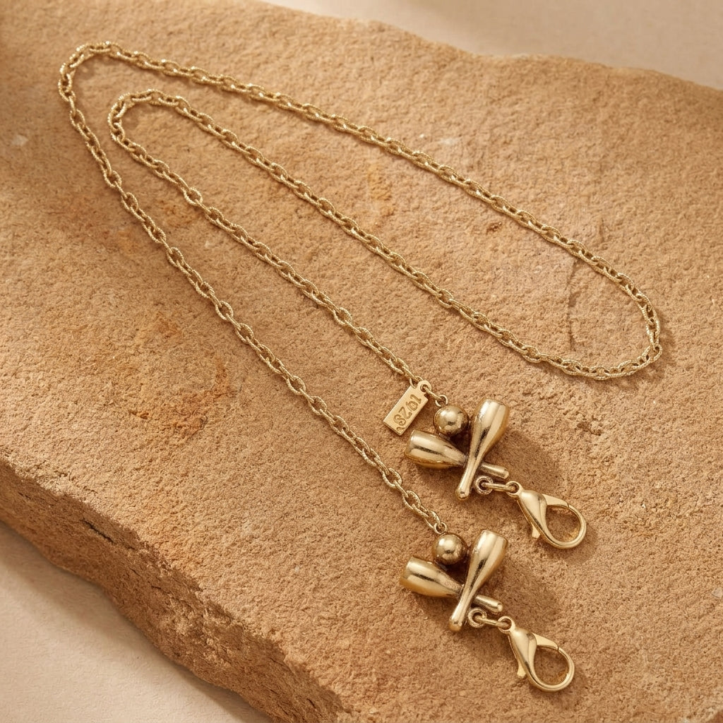 Gold tone Bowling Pins & Ball Face Mask Chain Holder necklace on a textured beige stone surface
