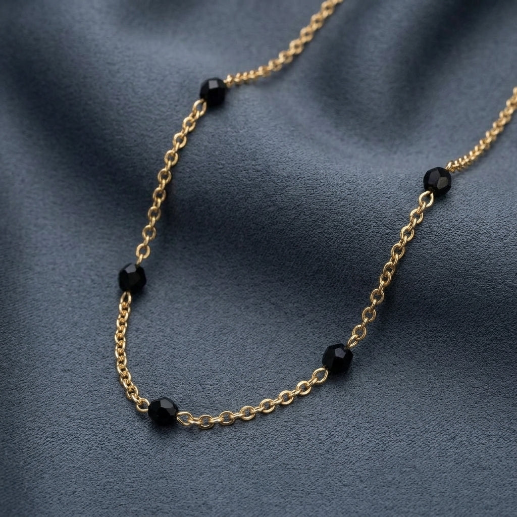 Jet Black Faceted Glass Beaded Necklace resting on gray smooth fabric